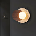 Layered circular wall sconce with travertine and walnut discs, lit round globe