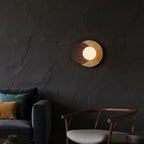 Circular layered wall sconce with travertine-look finish and lit globe