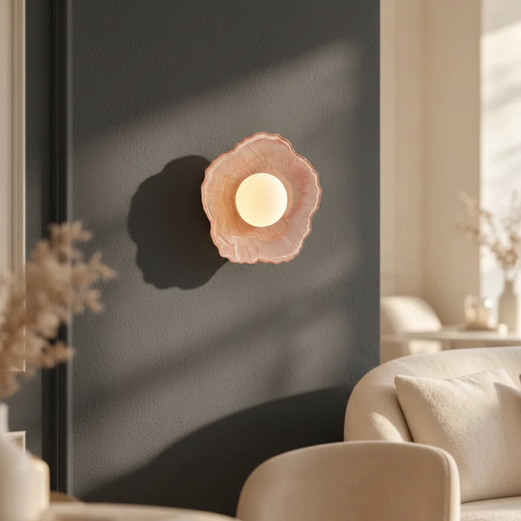 Coral pink textured petal wall sconce with glowing round bulb, floral disc design