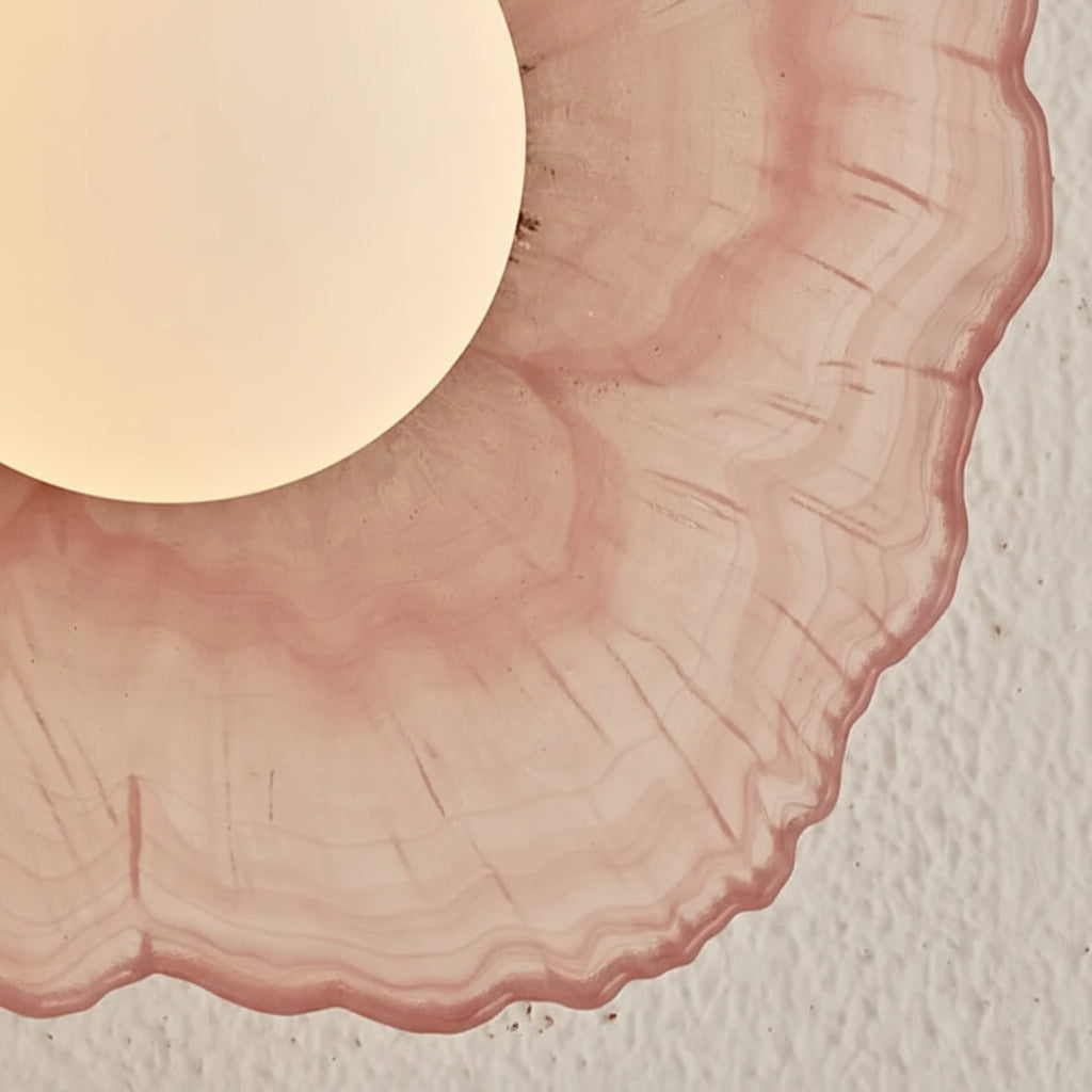 Close-up of coral pink petal-textured glass shade with white lamp insert, curved edge