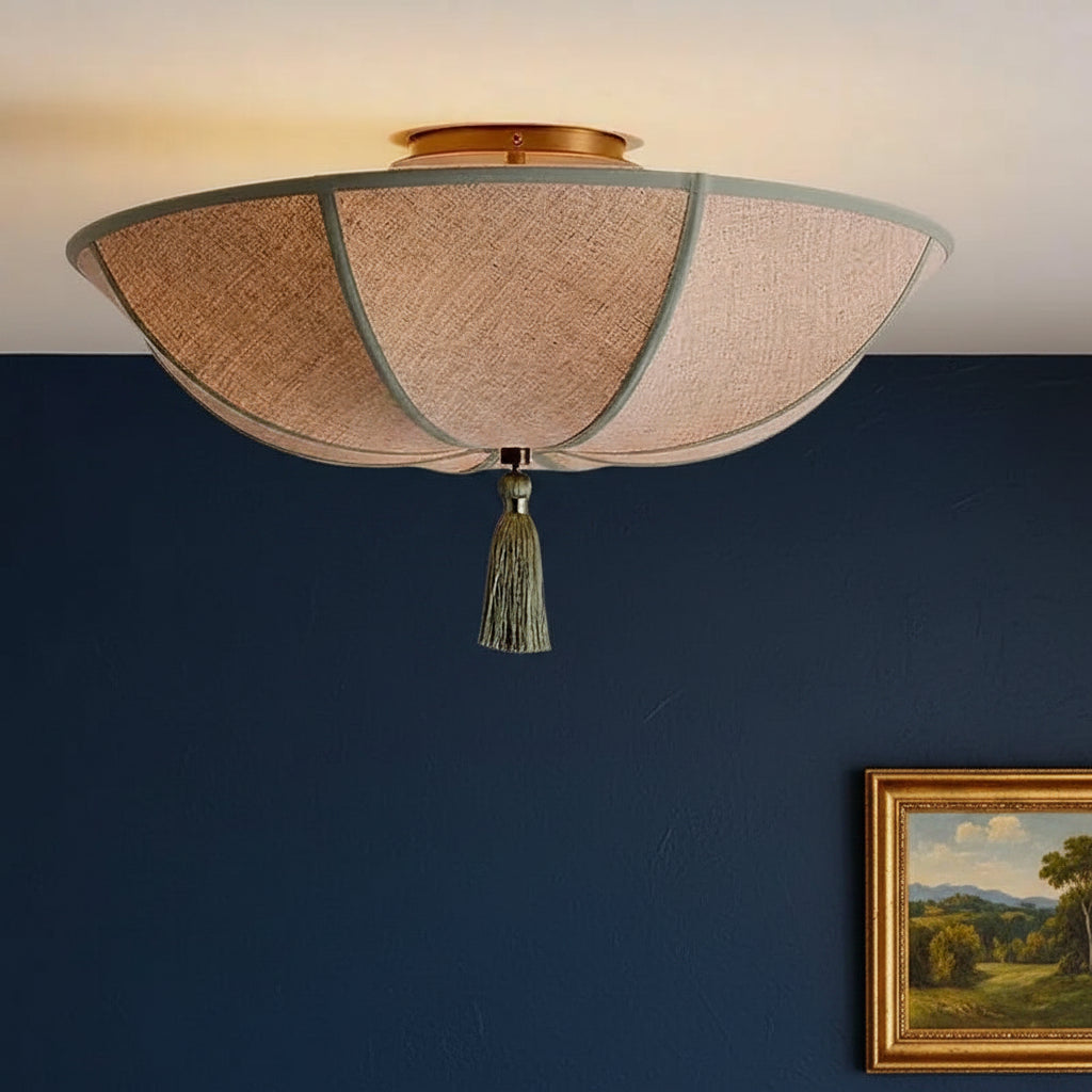 Round ceiling light fixture with pleated beige fabric shade, teal frame lines, gold cap, tassel