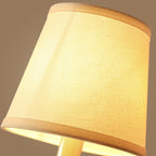 Conical fabric shade with warm light glow on a brass wall sconce