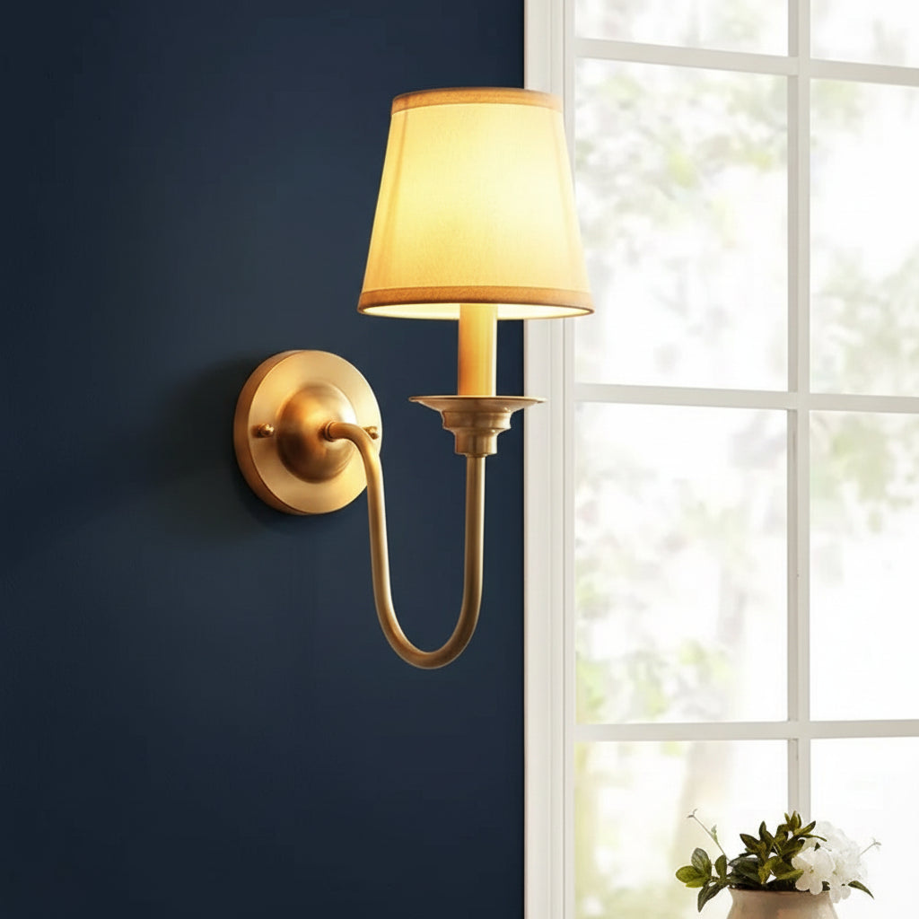 Gold-tone wall sconce with conical shade, curved arm, and circular backplate