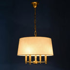 Fabric drum pendant light with white shade, gold chain, and multi-bulb candle-style base