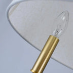 Pendant light bulb with clear glass and gold base under a white fabric drum shade