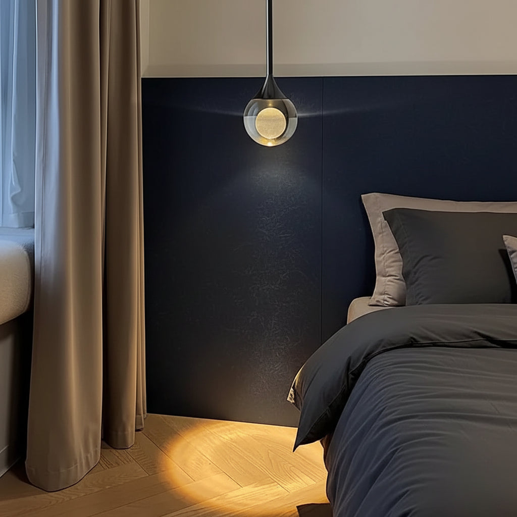 Teardrop pendant light hanging above bed, smoked glass shade with warm glowing inner globe