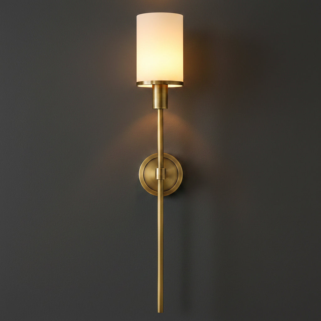 Gold vertical wall sconce with cylindrical frosted shade and circular backplate