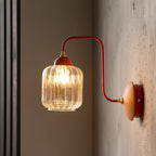 Red curved arm sconce with ribbed glass shade, round wood backplate, warm light on