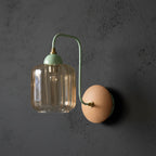 Green curved arm wall light with ribbed cylindrical glass shade and round wood backplate