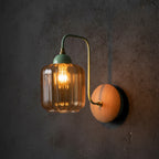 Green curved arm sconce with ribbed glass shade and round wood backplate, lit bulb