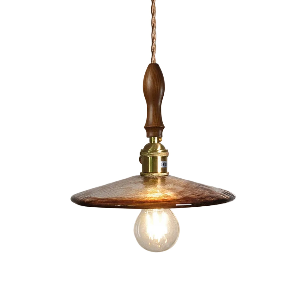 Amber glass saucer style pendant light with brass socket, warm bulb, and brown cord