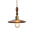 Amber glass saucer style pendant light with brass socket, warm bulb, and brown cord