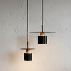 Set of two cylindrical pendant lights with black shades and warm glowing bulbs