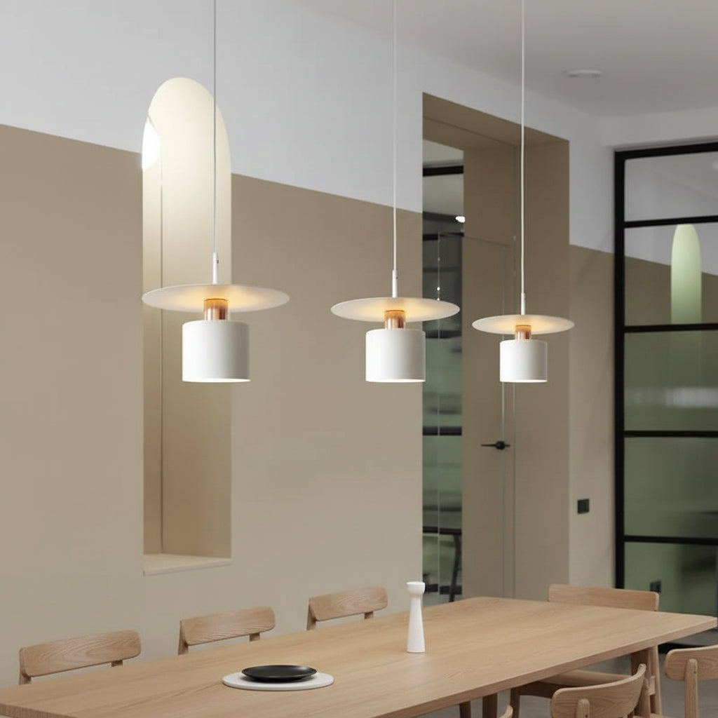 Multiple white cylindrical pendant lights with warm glowing bulbs