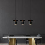 Multiple cylindrical pendant lights with black shades and warm glowing bulbs