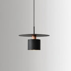 Single black cylindrical pendant light with a warm glowing bulb