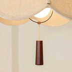 Brown pendant light finial with thin gold cord hanging from the fabric shade