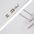 White tubular LED wall sconce close-up with adjustable joints and brass connector ends
