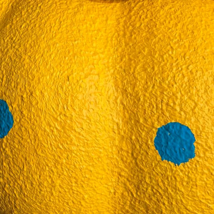 Close-up of yellow fabric shade with blue dot pattern and textured surface
