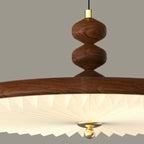 Walnut UFO-style pleated pendant light close-up of wood stem and shade