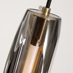 Close-up of reflective tubular glass shade with brass top fitting and dark cable