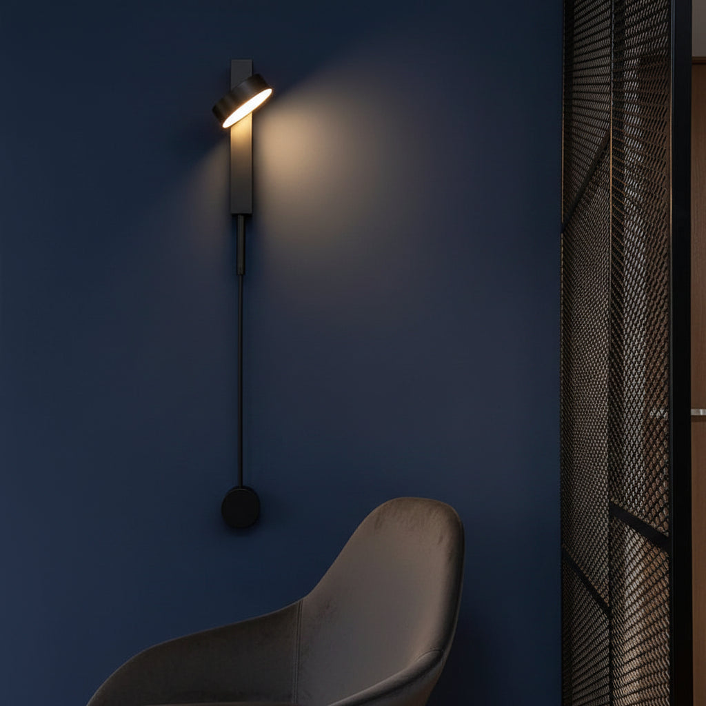Black vertical wall sconce with cylindrical shade and round pull-switch knob, warm light