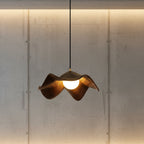 Curved wooden pendant light with warm glowing bulb and dark hanging cord