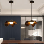 Pair of curved wooden pendant lights with warm glowing bulbs and dark cords