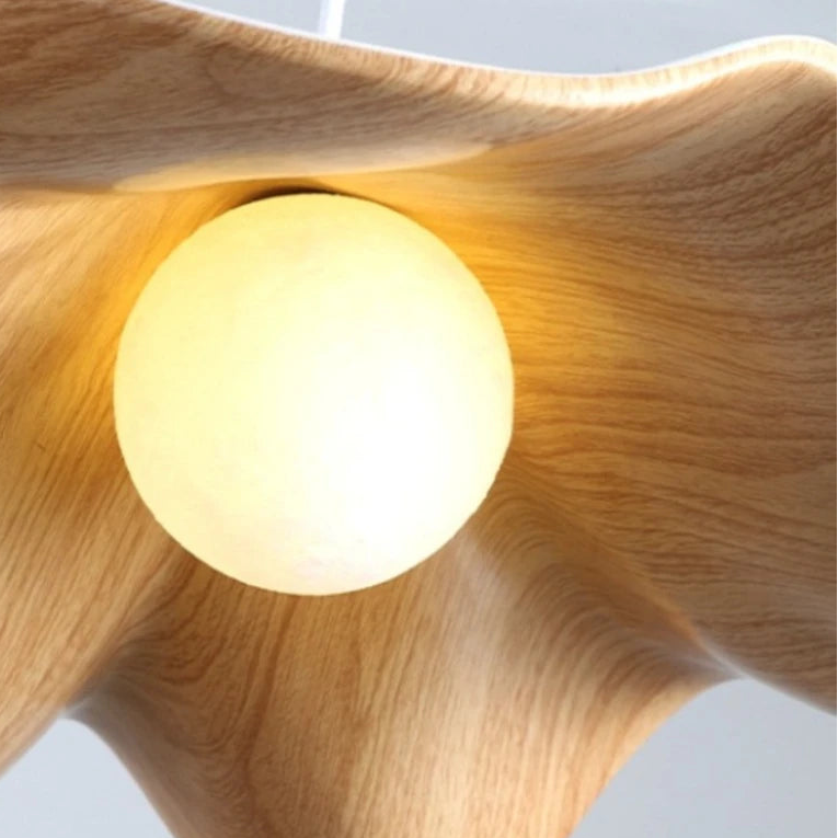 Close-up of warm glowing bulb inside curved wood pendant light shade