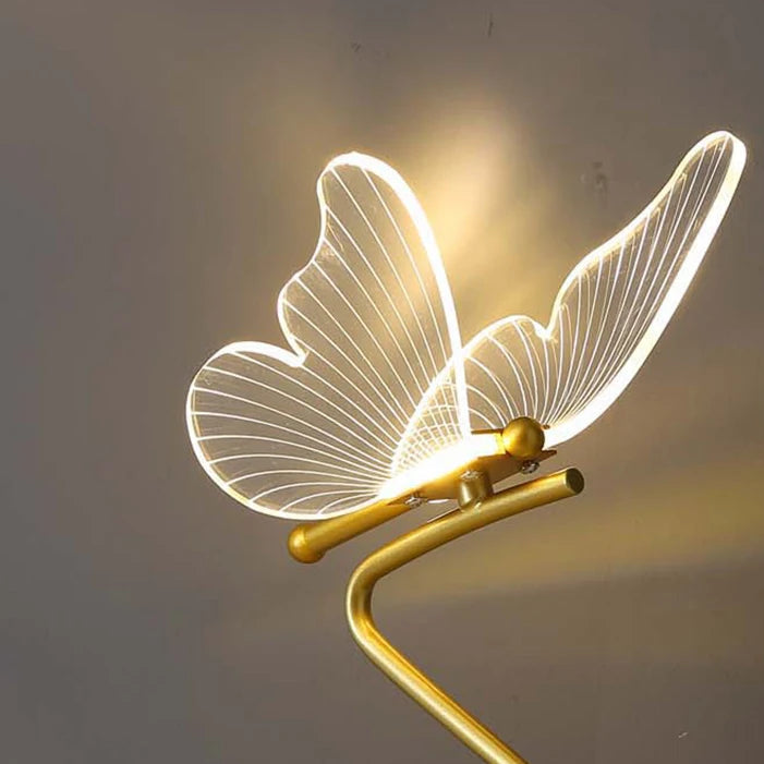 Glowing gold butterfly table lamp with illuminated wire wing design on curved base