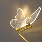 Glowing gold butterfly table lamp with illuminated wire wing design on curved base