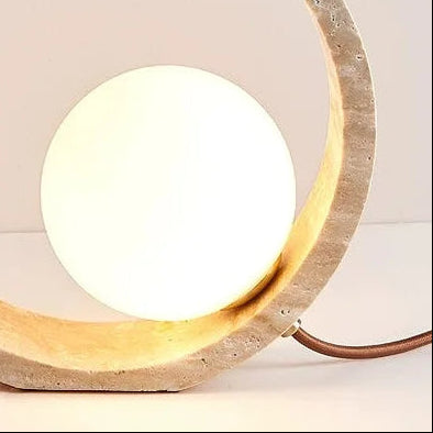 Round globe table lamp with glowing bulb inside textured ring and brown cord