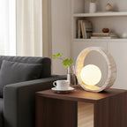 Travertine ring table lamp with glowing round glass globe in open ring frame