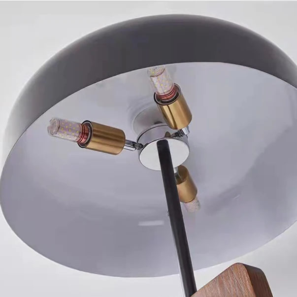 Close-up of tripod table lamp underside with three bulbs under gray dome