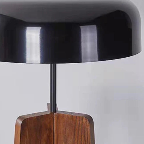 Tripod table lamp with black dome shade and walnut tripod legs, close-up