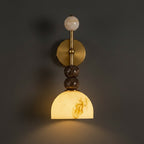 Brass postmodern wall sconce with round backplate, stacked stone spheres, and dome shade