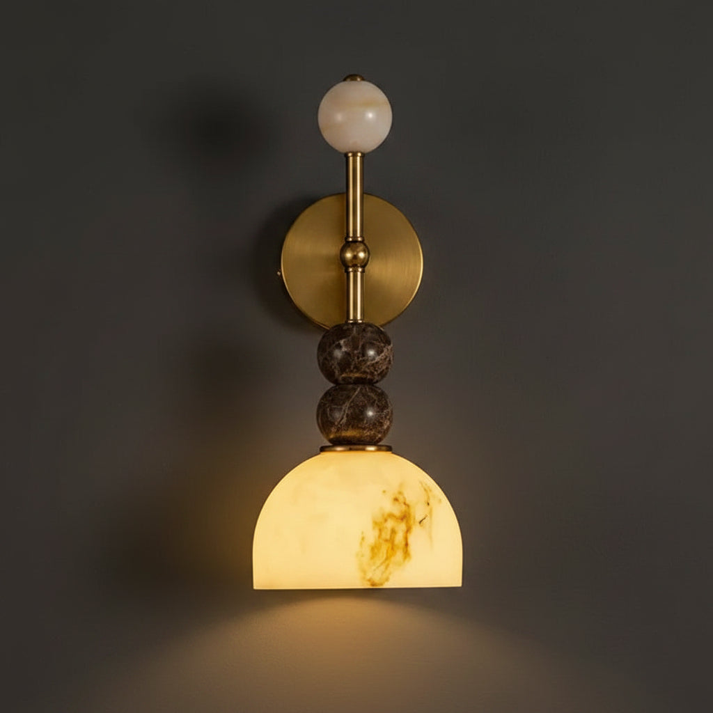 Brass postmodern wall sconce with round backplate, stacked stone spheres, and dome shade