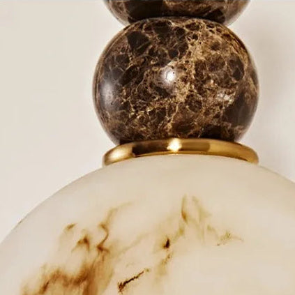 Close-up of marble sphere and frosted dome shade on brass wall sconce