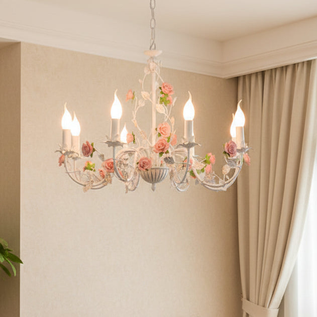 Floral arm chandelier with white arms and pink rose blooms, hanging above curtains