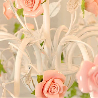 Close view of pink roses and white scrollwork on floral chandelier
