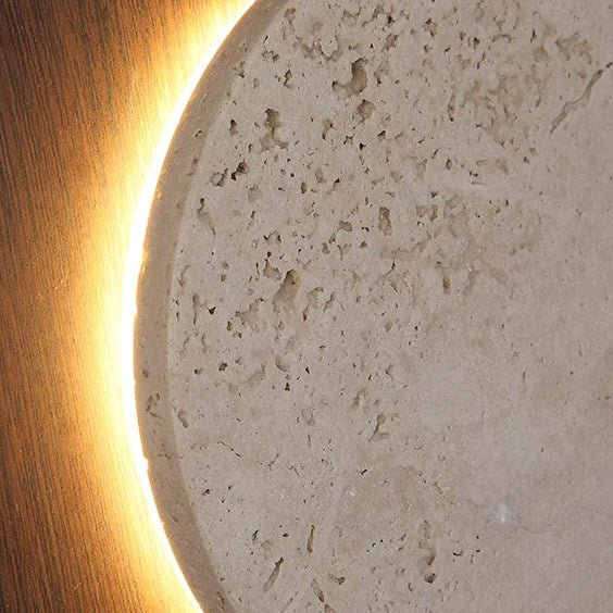 Close-up of glowing edge around speckled travertine panel in a round wall sconce