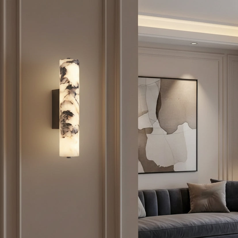 Tubular cylindrical marble wall sconce with black mount, glowing diffuser on wall