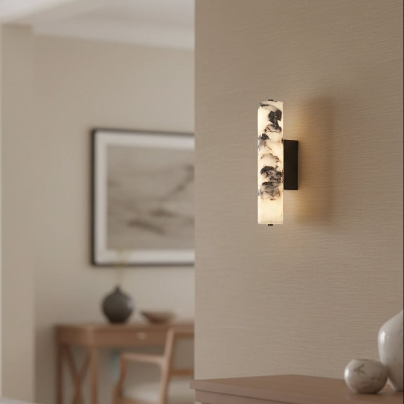 Cylindrical marble wall light with dark back plate and soft lit diffuser