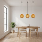 Set of three woven rattan globe pendant lights suspended on black cords