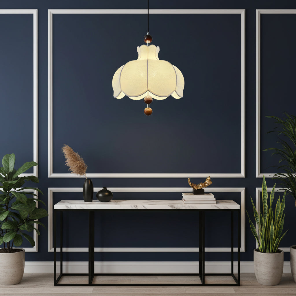 Cream scalloped pendant light hanging above a console table with brown wooden balls
