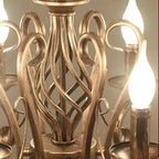 Antique gold cage chandelier close-up with curved lattice and candle holder tops
