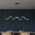 Minimalist wavy linear LED pendant light with dark ceiling canopy and warm glow