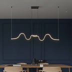 Minimalist wavy linear LED pendant light with dark ceiling canopy and warm glow