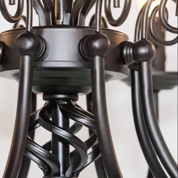 Scroll arm chandelier detail with curved metal stems and candle sockets, dark bronze finish