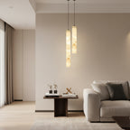 Set of three slim tubular alabaster pendant lights with black cords.